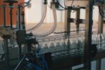 B.Mek – Nastro trasportatore con due sistemi di riempimento Nastro trasportatore industriale con due punti di riempimento e contenitori in vetro