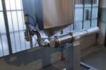 Vista laterale di dosatrice con tramoggia rettangolare e supporto metallico